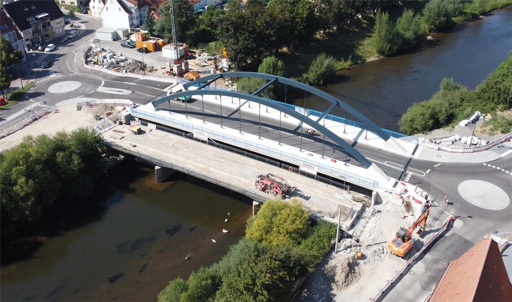 Die unterhalb des neuen Bauwerks liegende alte Brücke wird für den Abbruch in zwölf Teile zersägt, die vom Mobilkran ans Ufer gehievt und dort zerkleinert werden. Foto: Schramm