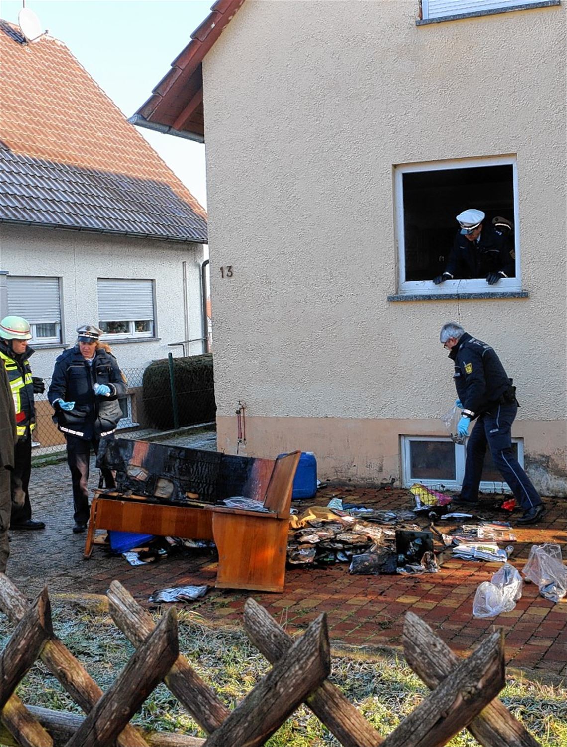 Die verkohlte Eckbank ist ins Freie gebracht worden und wird inspiziert. Foto: Sadler