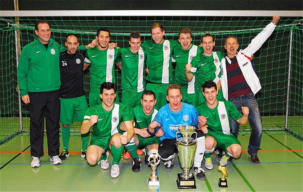 Diese Fußballer entführen den großen, glänzenden Wanderpokal aus Mühlacker: Der FV Grünwinkel freut sich über den Turniersieg beim Senderstadtcup in der Enztalsporthalle. 