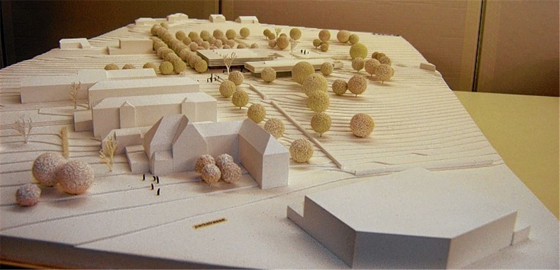 Diesen Entwurf des Büros Wittfoht Architekten hat die Jury auf Platz eins gesetzt. Oberhalb von Friedhof und Schule (Bestandsgebäude vorne links) sollen zwei Baukörper entstehen.