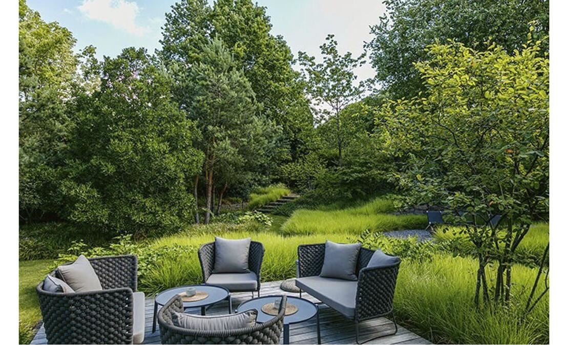 Dieser Garten wird von Grün dominiert. Er ist unaufdringlich. Die Terrasse liegt auf der Waldlichtung.