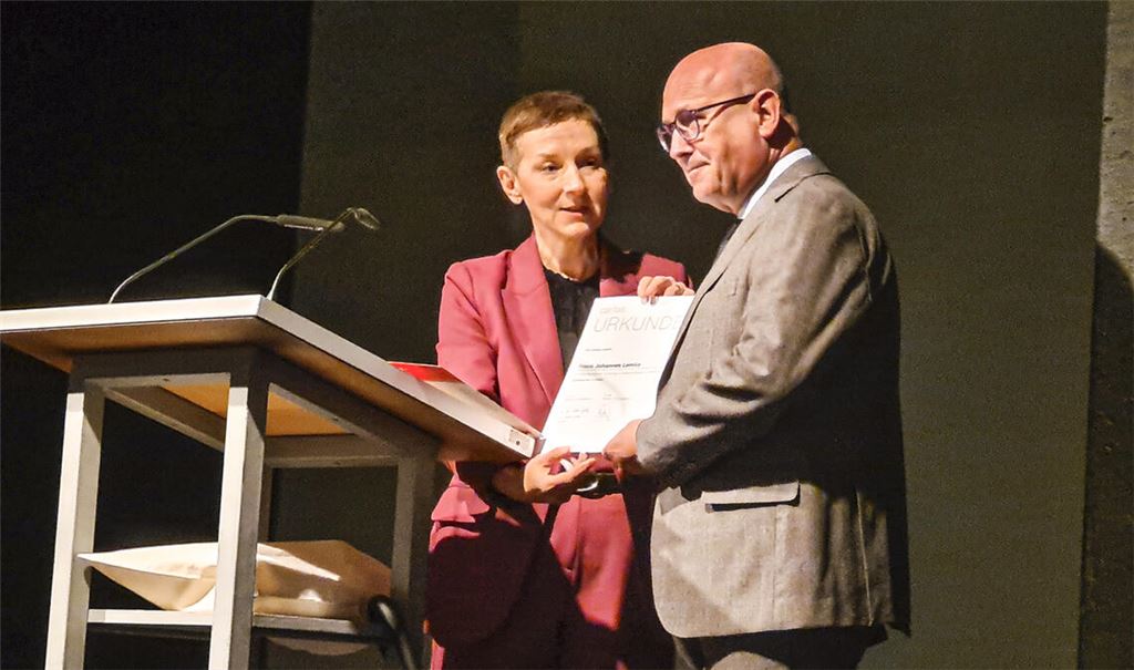 Diözesan-Caritasdirektorin Birgit Schaer von der Erzdiözese Freiburg überreicht Lemke zu seinem Abschied eine Urkunde. Außerdem erhält er die silberne Verbandsehrennadel, einen roten Regenschirm und einen Stein aus dem Münster. Foto: Metzbaur