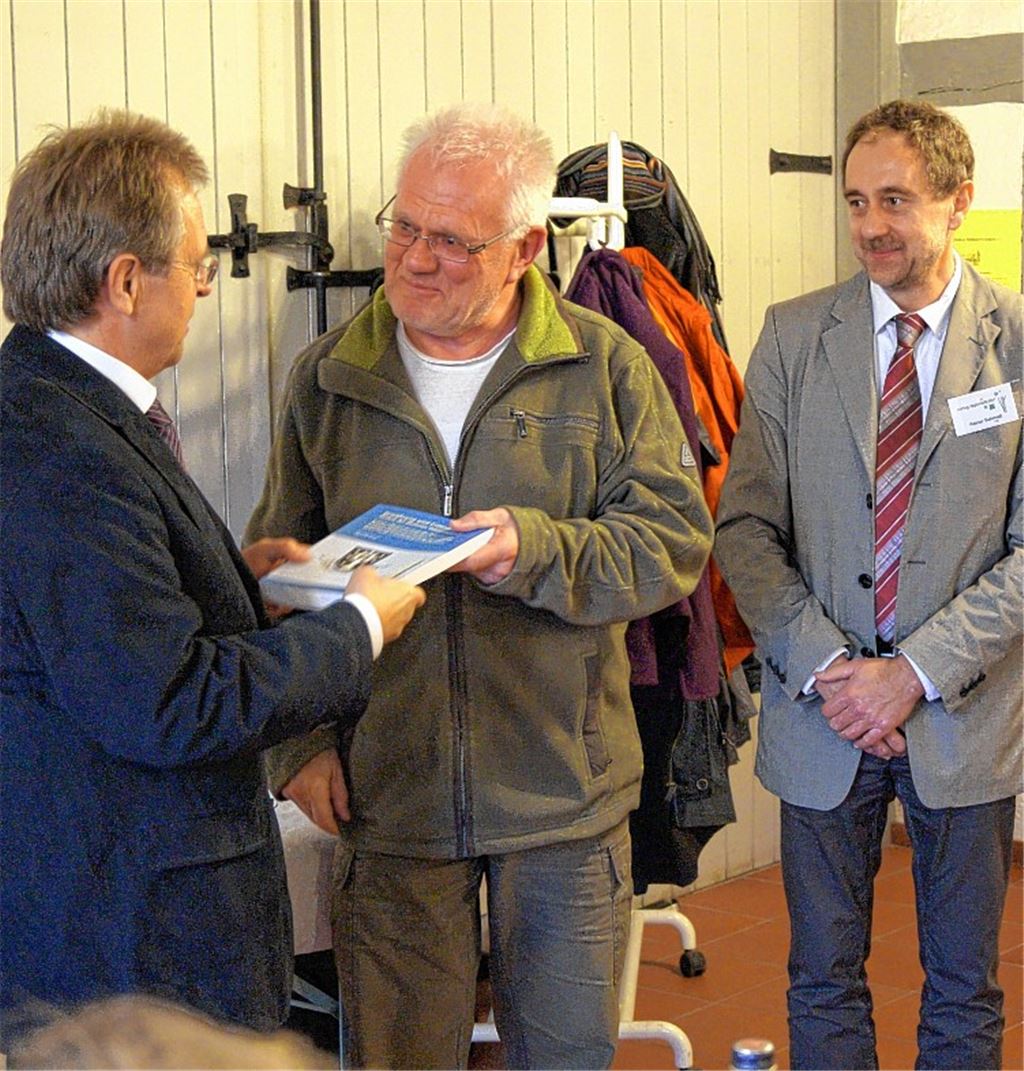 Dr. Albert de Lange (Mitte) überreicht dem Ötisheimer Bürgermeister Werner Henle (li.) ein Exemplar seines Buches. Mit dabei ist Reiner Schmidt, Geschäftsführer des herausgebenden Verlags Regionalkultur. Foto: Czop