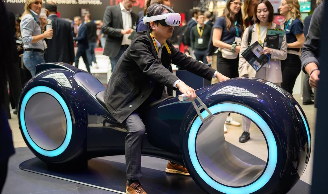 Durch eine Augmented-Reality-Brille schauend sitzt ein Gast auf einem fiktiven Gefährt bei der Industriemesse Hannover.