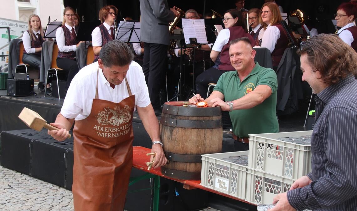 Eberhard Zucker beim Fassanstich zum Vaihinger Straßenfest. Die Musikerinnen und Musiker aus Kleinglattbach sind gespannt. Eine Blinddichtung bremst den Stadtrat aus. Doch nach 26 Schlägen klappt es schließlich doch noch. Foto: Arning