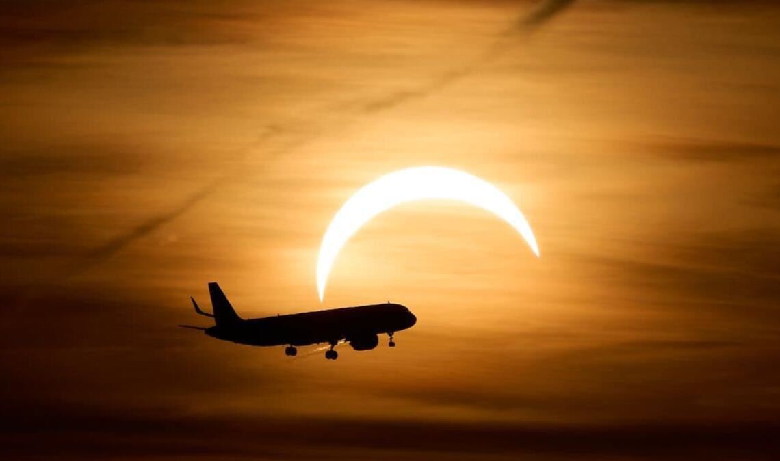 Ein Airbus A321 aus London fliegt während der partiellen Sonnenfinsternis im Landeanflug auf den Flughafen Berlin Brandenburg (BER) vor der teilweise vom Mond verdeckten Sonne. 