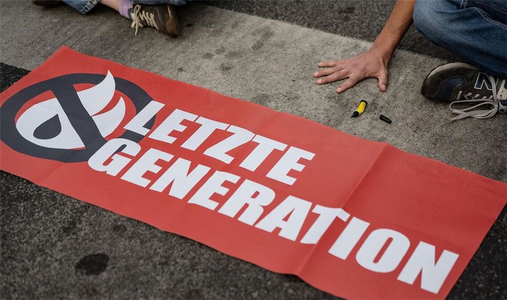 Ein Aktivist der Gruppe "Letzte Generation", der seine Hand selbst auf der Straße festgeklebt hat, blockiert eine Kreuzung in Göttingen.