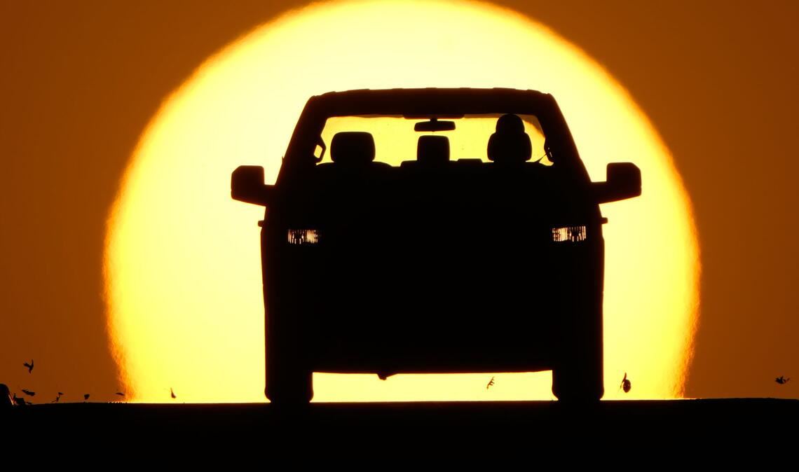 Ein Autofahrer wird von der untergehenden Sonne angestrahlt.