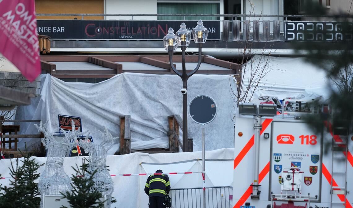 Ein Feuerwehrmann beobachtet die abgeriegelte Bar Le Constellation, in der ein verheerendes Feuer während der Silvesterfeierlichkeiten Tote und Verletzte forderte.