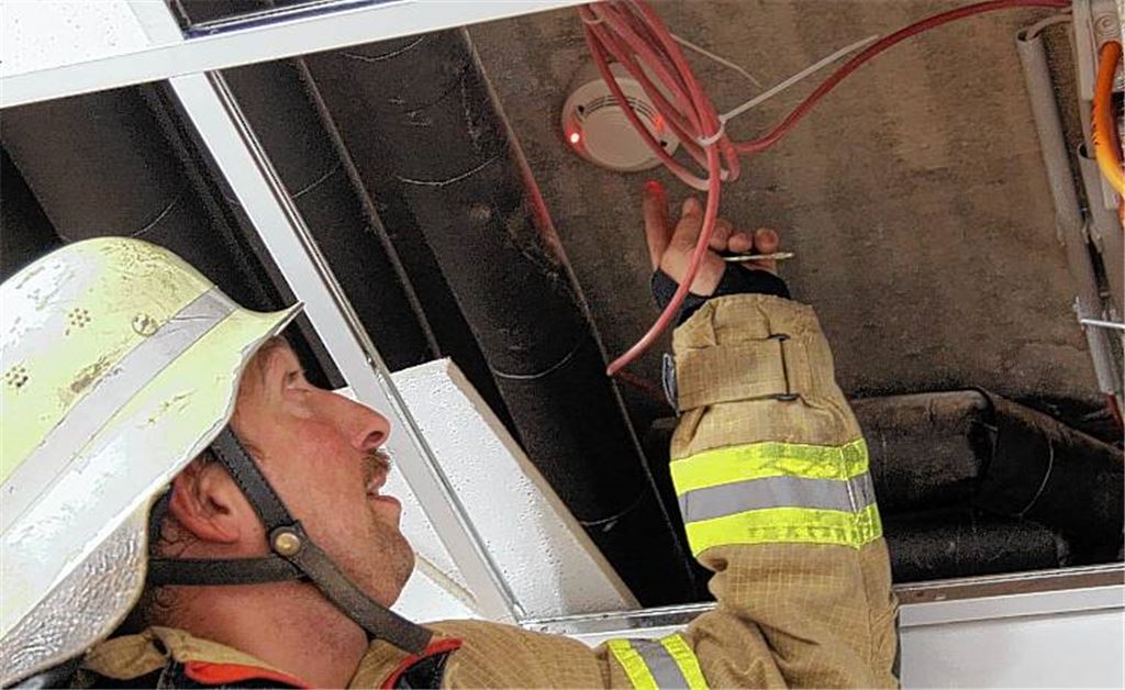 Ein Feuerwehrmann zeigt den Brandmelder in der Decke, der Alarm geschlagen hat. 