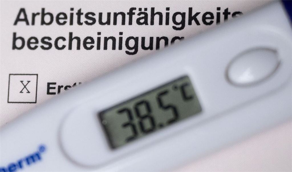 Ein Fieberthermometer liegt auf einer Arbeitsunfähigkeitsbescheinigung (gestellte Szene).