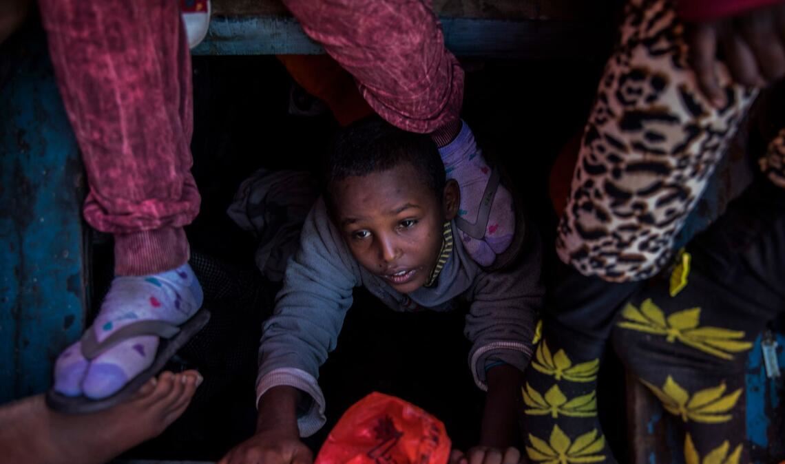 Ein Flüchtlingskind aus Eritrea versucht an der Küste zu Libyen, an Bord eines überfüllten Holzbootes hinaufzuklettern.