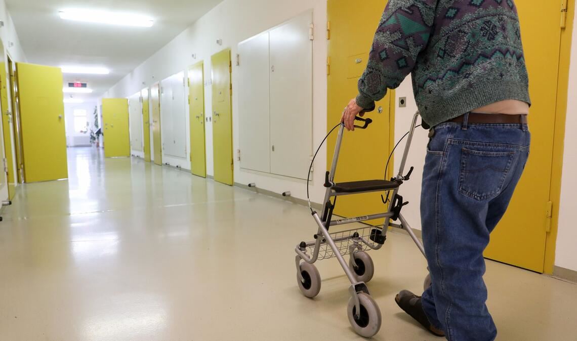 Ein Häftling im Rentenalter geht mit einem Rollator über den Flur im Seniorentrakt der JVA Waldheim.