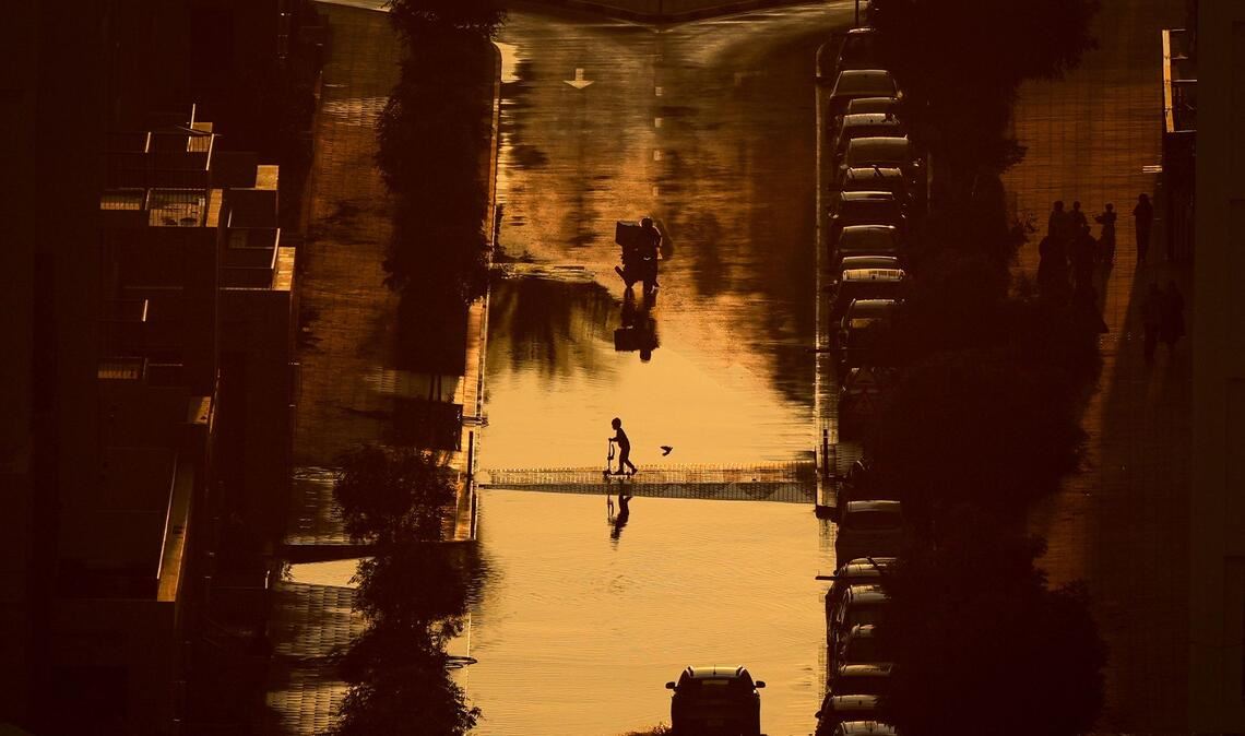 Ein Junge überquert eine mit Regenwasser gefüllte Straße in Schardscha, Vereinigte Arabische Emirate.