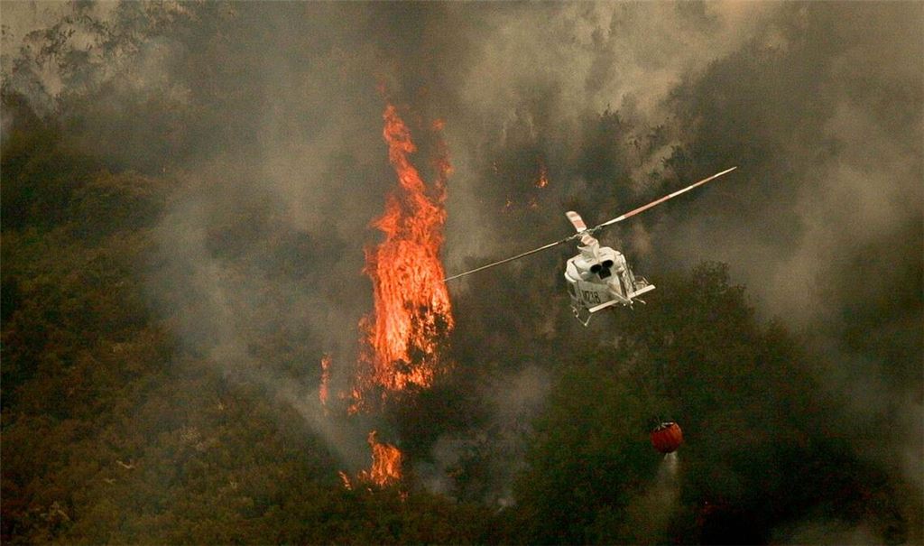 Ein Löschhubschrauber wirft Wasser über einem Feuer in der spanischen Provinz Ourense ab.