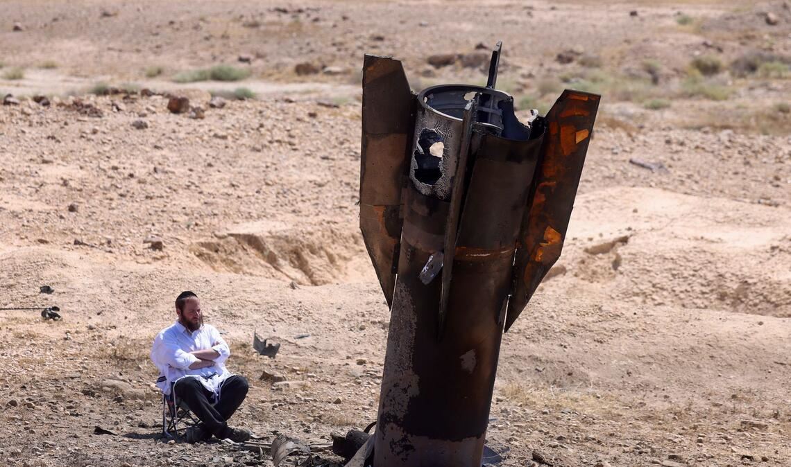 Ein Mann betrachtet das Wrack einer Rakete, die nach einem iranischen Angriff im Westjordanland aus dem Boden ragt.