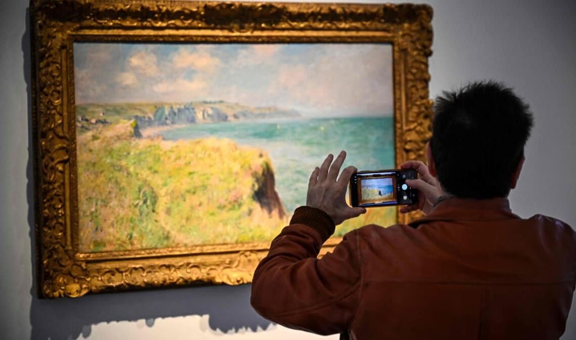 Ein Mann fotografiert ein Gemälde von Claude Monet. Ein zuvor nie öffentlich ausgestelltes Gemälde des Malers Claude Monet ist in Paris zum Rekordpreis versteigert worden (Symbolfoto).
