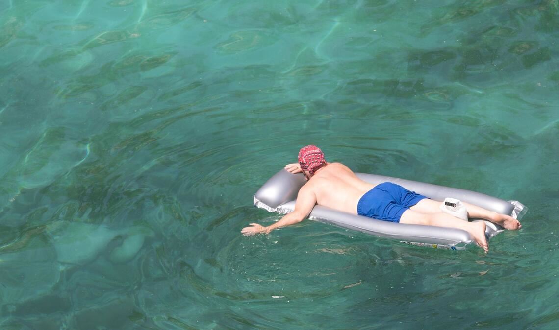 Ein Mann genießt das Meer in seiner aufblasbaren Matratze am Strand von Cala Pi auf Mallorca.