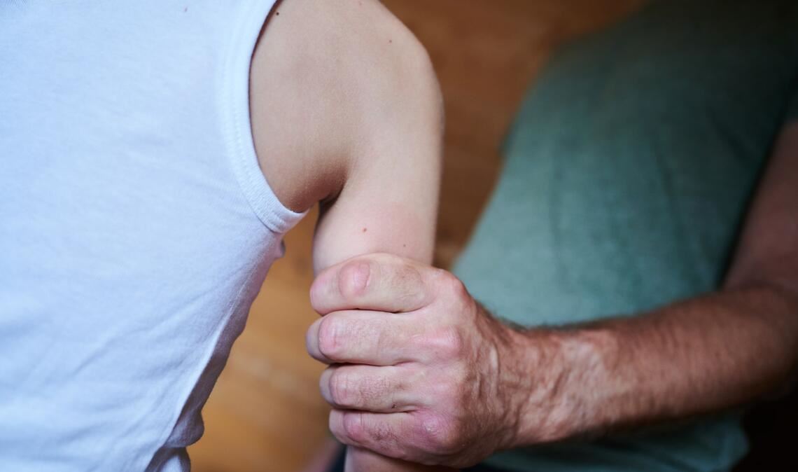 Ein Mann hält ein Kind fest am Arm (gestellte Szene). (Symbolbild)