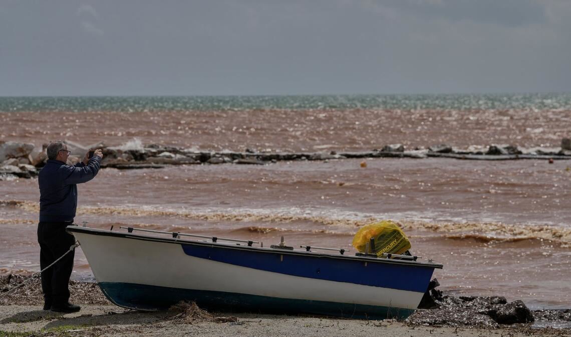 Ein Mann macht Fotos am Strand von Marathon, nachdem schwere Stürme über Nacht große Schäden verursacht haben.