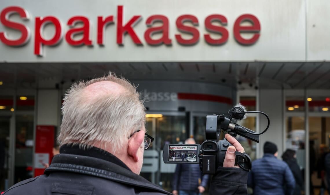 Ein Medienvertreter steht mit einer Kamera vor der Sparkassenfiliale in Buer.