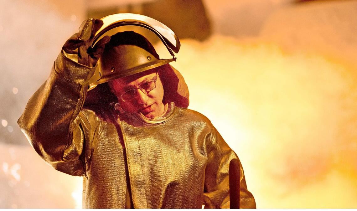 Ein Mitarbeiter der Salzgitter AG steht – gut geschützt – vor einem Hochofen.