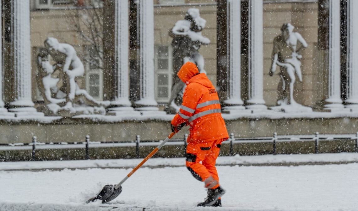 Ein Mitarbeiter der Stadtreinigung Potsdam befreit eine Tram-Haltestelle vom Schnee.