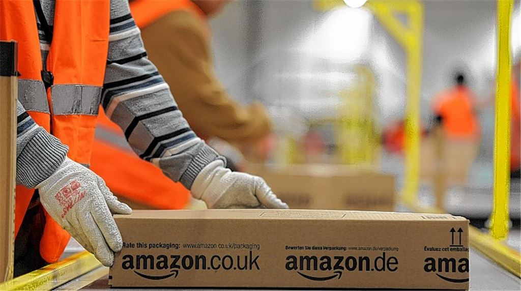 Ein Mitarbeiter der Versandabteilung des Amazon Logistikzentrums in Pforzheim legt ein fertig verpacktes Paket auf ein Fließband. Die Arbeitsbedingungen bei dem Online-Händler sind immer wieder Gegenstand von öffentlichen Diskussionen. In Pforzheim versucht der Betriesbsrat, die Situation zu verbessern. Foto: dpa