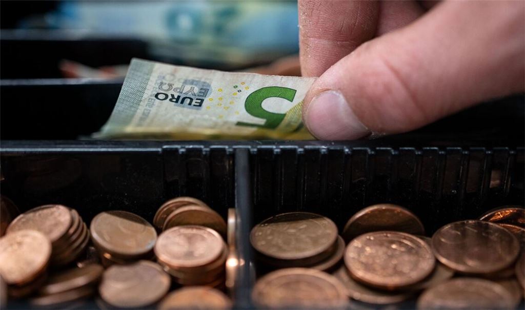 Ein Mitarbeiter eines Einzelhandelsgeschäfts nimmt einen 5-Euro-Schein aus einer Einkaufskasse (Symbolbild).