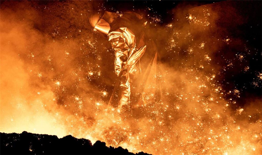 Ein Mitarbeiter reinigt in einem Stahlwerk in Salzgitter die Abstichrinne am Hochofen.