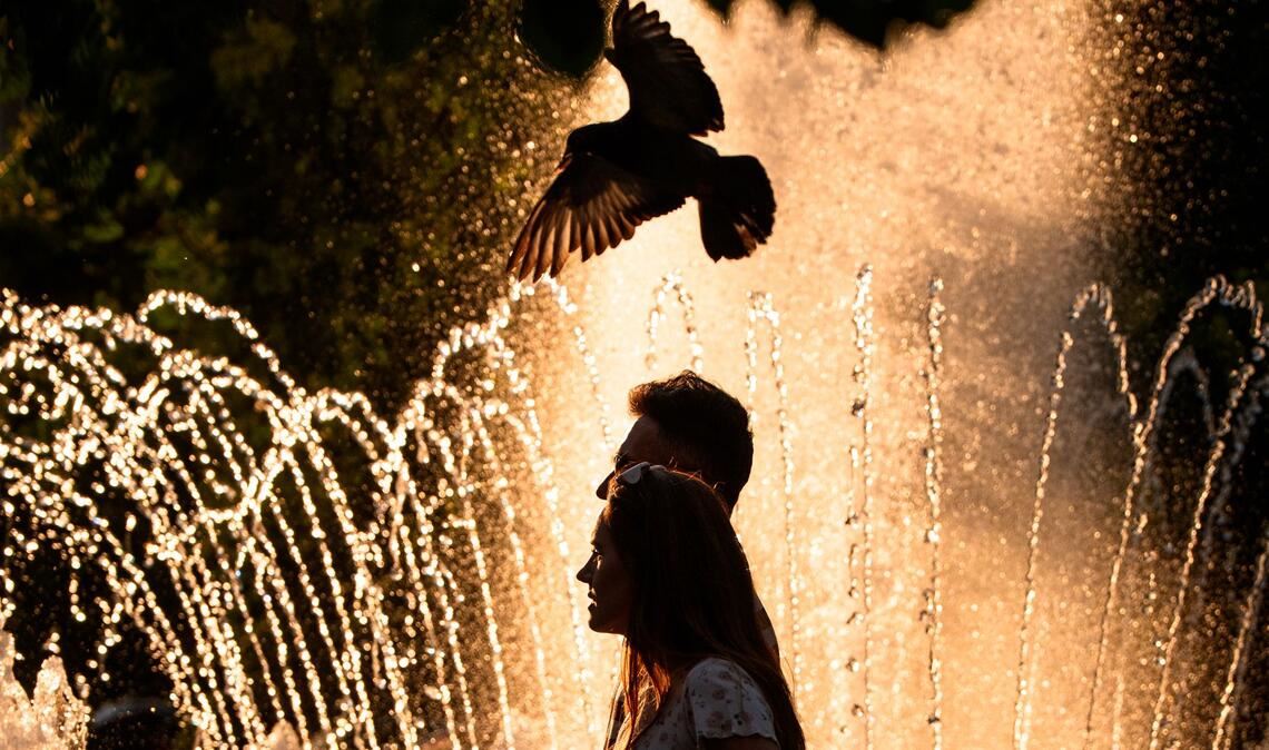 Ein Paar geht an einem Springbrunnen in Bukarest vorbei, während der nationale Wetterdienst für Teile des Landes in den kommenden Tagen eine Hitzewarnung der Stufe "Rot" herausgegeben hat.