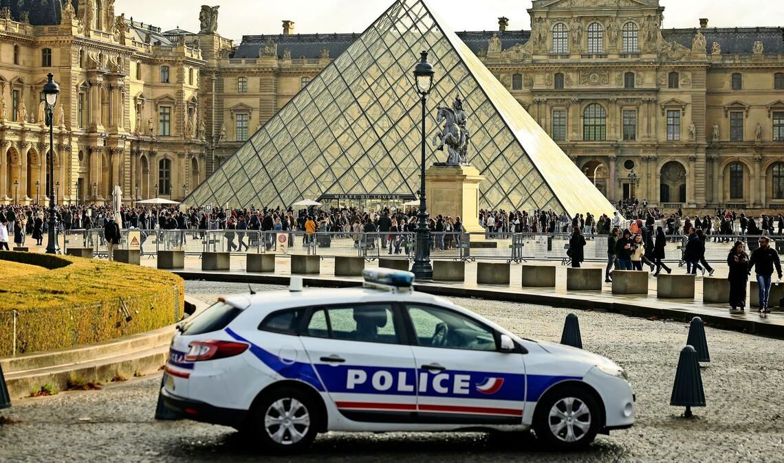 Ein Polizeiauto parkt im Hof des Louvre während Besucher vor der Glaspyramide in einer Schlange stehen. (Symbolbild)