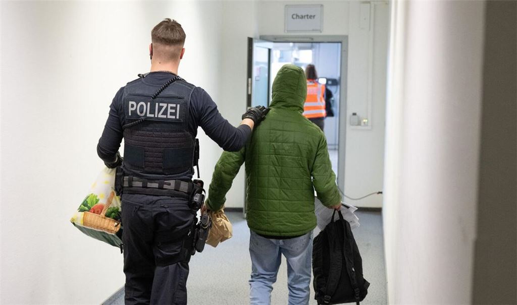 Ein Polizeibeamter bringt einen Mann zu einem Abschiebeflug (Symbolbild).