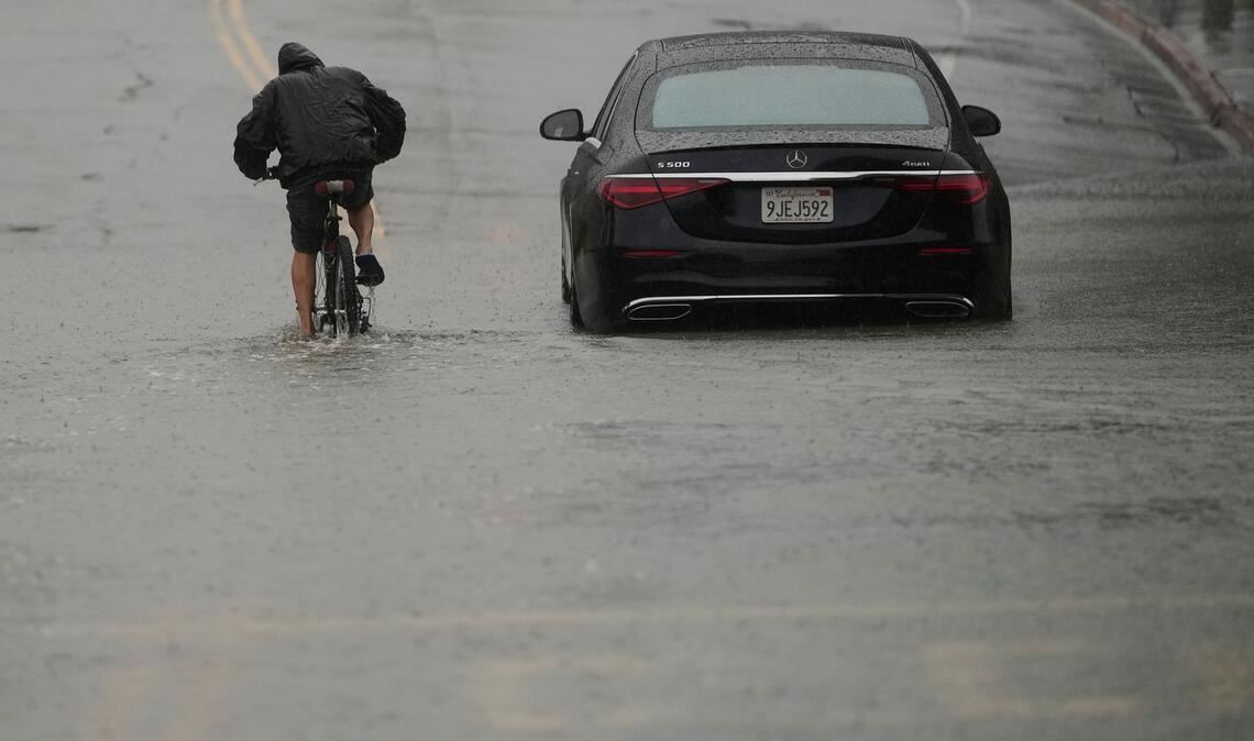 Ein Radfahrer fährt durch eine überflutete Straße.