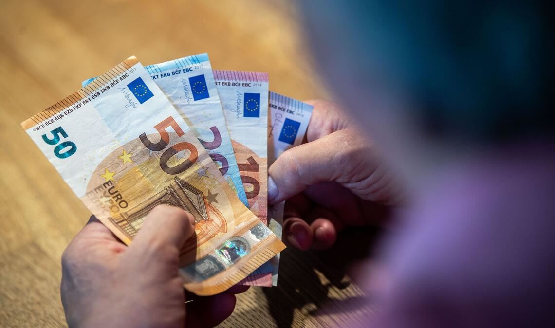Ein Rentner  sitzt an einem Tisch und zählt Geld. Fast die Hälfte der Menschen in Deutschland macht sich einer Umfrage zufolge Sorgen um ihre finanzielle Lage im Alter.