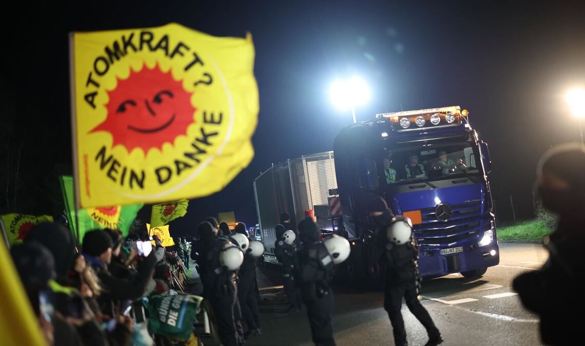 Ein Schwertransporter mit einem Castor-Behälter fährt an Teilnehmer einer Anti-Atomkraft-Demonstration vorbei.