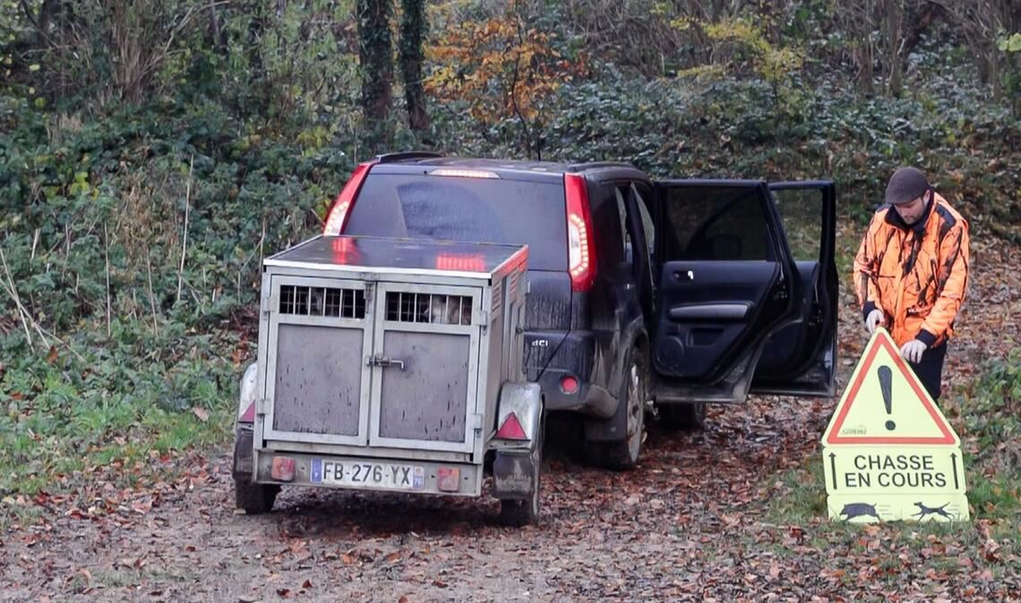 Ein französischer Jäger stellt ein Schild auf, das Spaziergänger vor einer Drückjagd warnt.