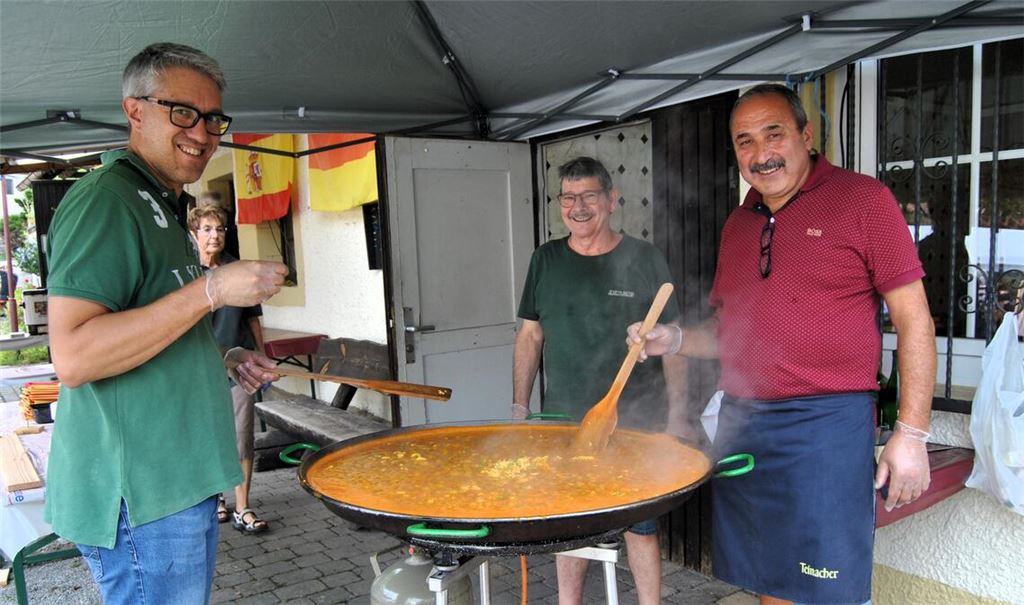 Ein gefragter Fixpunkt im Angebot ist die in der Riesenpfanne von Jose Guzman (Mitte) und Ali Ekiz (re.) unter Mithilfe von Vorstandsmitglied Jochen Escalante zubereitete original spanische Paella. Die rund 130 Portionen sind schnell ausverkauft. Fotos: Haller