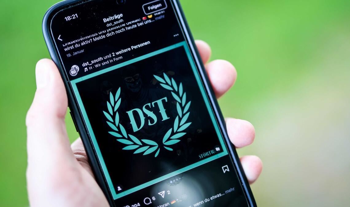 Ein junger Mann hält ein Smartphone in der Hand, auf der die Instragram-Seite von „Sturmtrupp Süd“ zu sehen ist (Symbolbild).