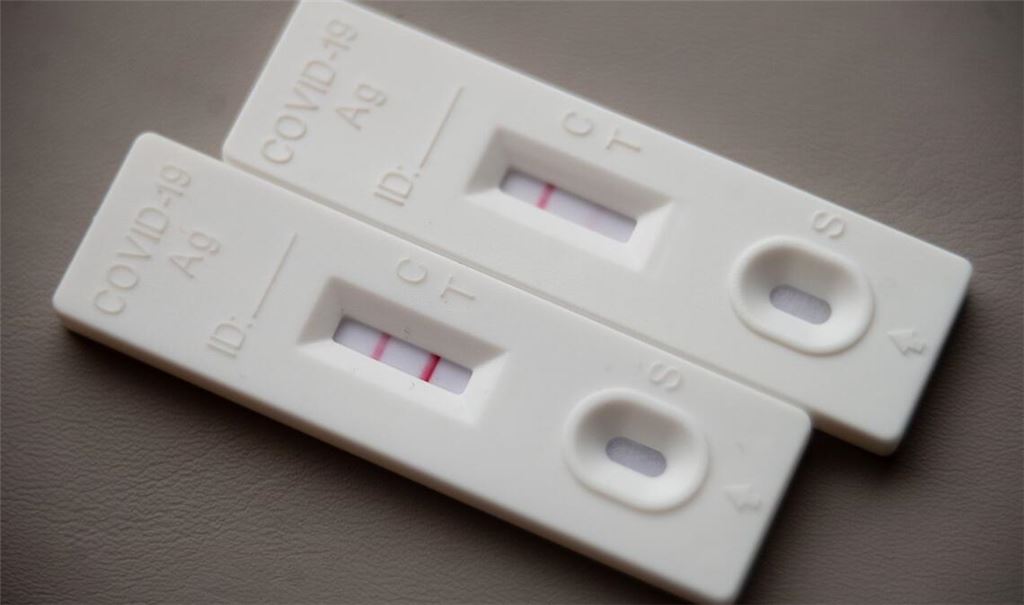 Ein positiver Corona-Schnelltest (li.) liegt auf einem Tisch neben einem Corona-Schnelltest, der schwach eine positive Linie hat.