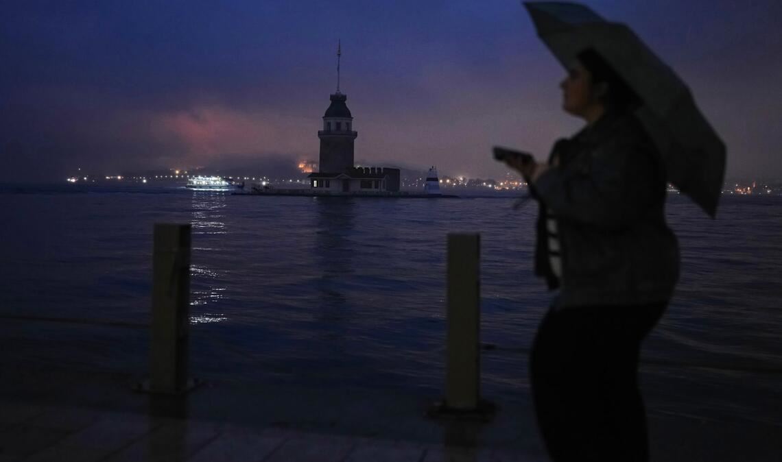 Eine Frau geht an einem regnerischen Tag in Istanbul am Jungfernturm am Bosporus vorbei.