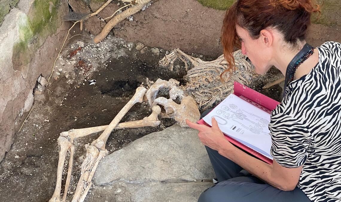 Eine Frau sitzt vor einem Skelett im Archäologiepark Pompeji.