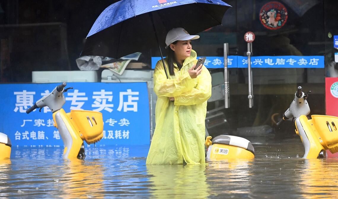 Eine Frau steht in Qinzhou auf einer mit Wasser vollgelaufenen Straße.