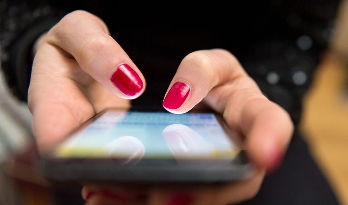 Eine Frau tippt auf einem Smartphone (Symbolbild)