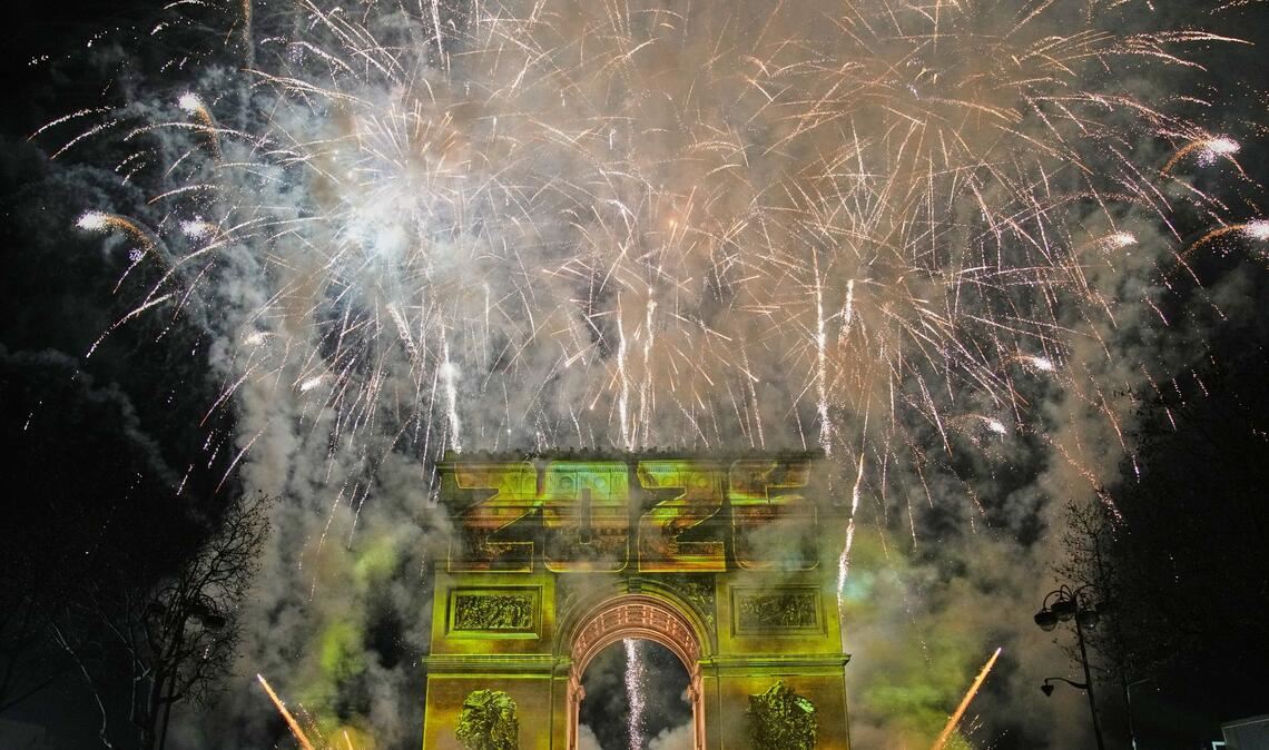 Eine Lichtshow wird auf den Arc de Triomphe projiziert, während ein Feuerwerk im Rahmen der Neujahrsfeierlichkeiten auf den Champs Elysees gezündet wird.
