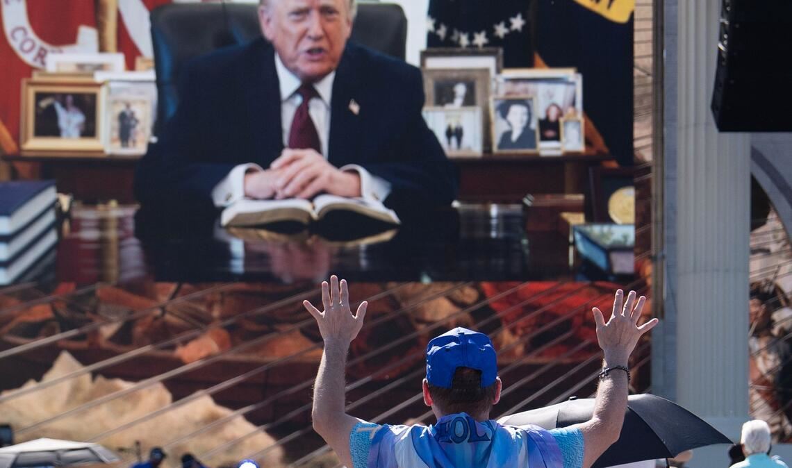 Eine Person betet, während eine aufgezeichnete Videobotschaft von US-Präsident Donald Trump abgespielt wird.