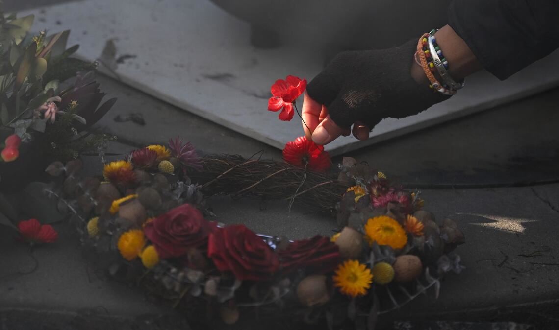 Eine Person legt eine Mohnblume an der Gedenkstätte "Für unser Land" während der Gedenkfeier für Aborigines und Torres-Strait-Insulaner (ATSIVA) im Rahmen des Anzac-Tags am Australian War Memorial in Canberra nieder.