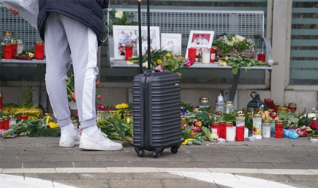 Eine Reisende schaut sich die Blumen, Kerzen und verschiedene Bilder im Wartehäuschen am Bahnhof zum Gedenken an die Opfer der Messerattacke an.