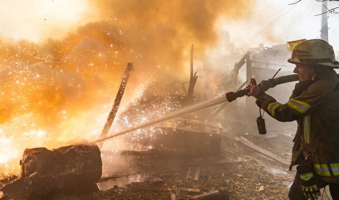 Eine Rettungskraft löscht einen Brand in Wohnhäusern, die bei einem russischen Angriff zerstört wurden.