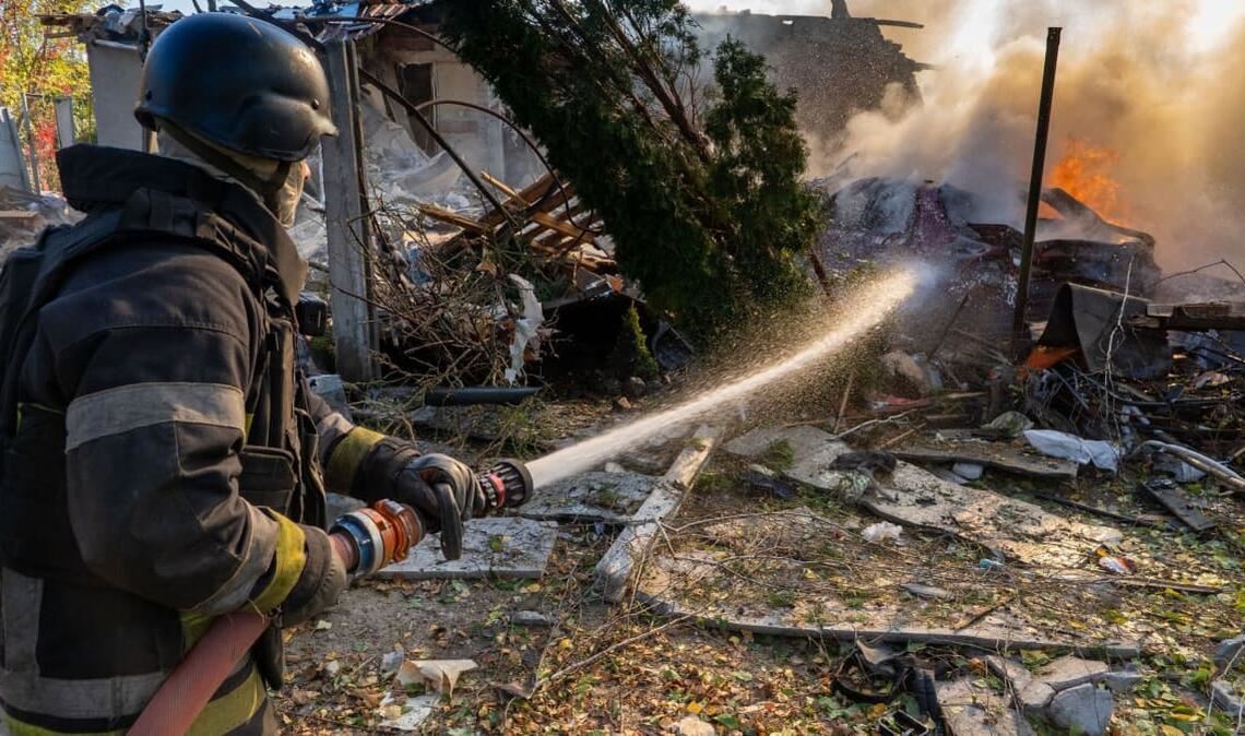 Eine Rettungskraft löscht einen Brand in Wohnhäusern, die bei einem russischen Angriff zerstört wurden.